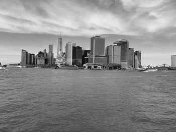 Modern buildings by river against sky in city