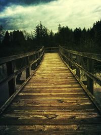 Wooden footbridge against cloudy sky