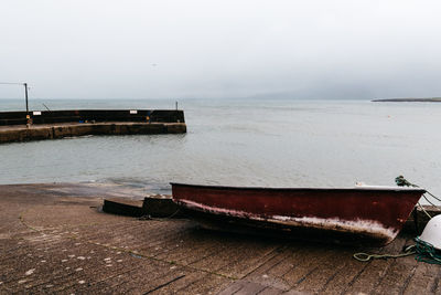 Abandoned boat at harbor against sky