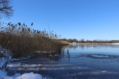 Frozen lake against clear sky during winter