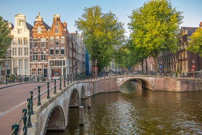 Bridge over canal amidst buildings against sky