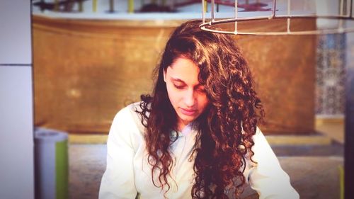 Young woman looking down while sitting outdoors