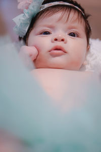 Close-up portrait of cute baby girl lying on bed