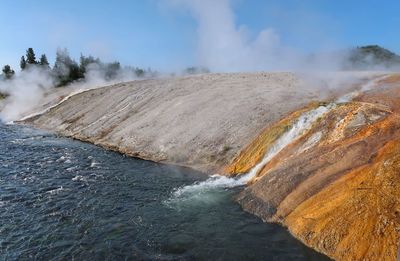 Landscape of a river flowing along a colorful steaming hot spring in yellowstone national park