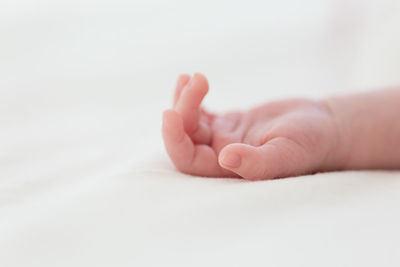 Cropped hand of baby lying on bed