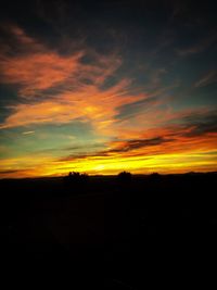 Silhouette landscape against dramatic sky during sunset