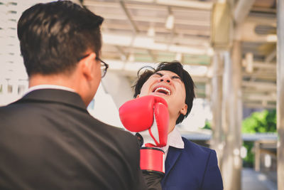 Rear view of mid adult businessman punching colleague