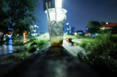 Close-up of beer glass against illuminated city