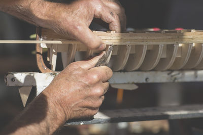 Close-up of man working on wooden boat model