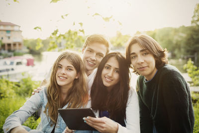 Portrait of confident teenagers with digital tablet at park