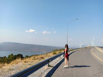 Rear view of woman on road against sky