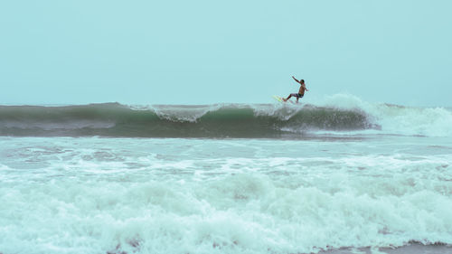 Man surfing in sea against clear sky