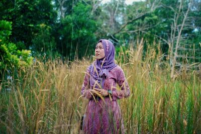 Portrait of young woman standing amidst plants