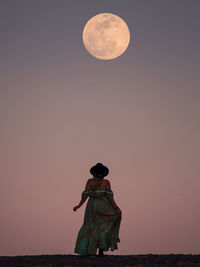 Rear view of man standing against moon in sky