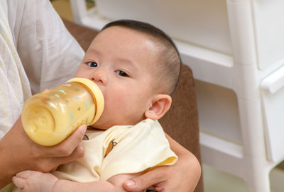 A portrait of cute newborn baby being fed by her mother using bottle, love and healthcare concept