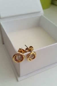 High angle view of gold earrings on white box