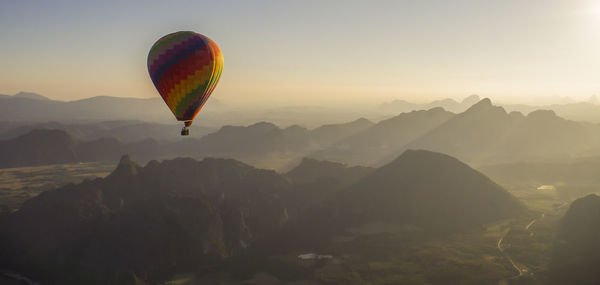 Hot air balloon flying over mountains against sky