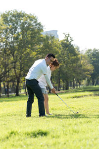 Full length of couple playing golf on field