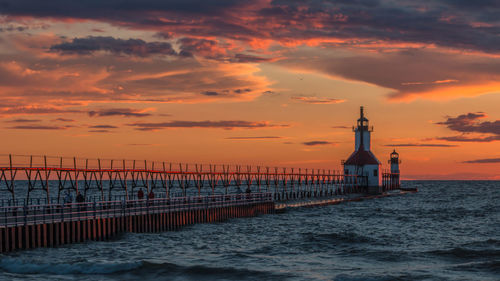 Scenic view of lake with pier against vivid backdrop colored clouds in the sky during sunset