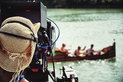 Rear view of cameraman filming people on boat