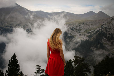 Rear view of woman standing on mountain against sky