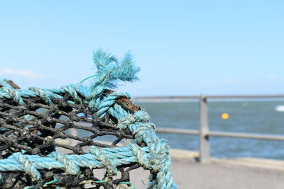 Close-up of fishing net on beach against clear blue sky