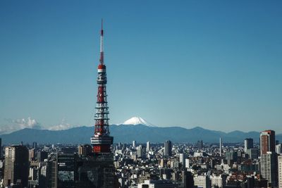 Communications tower and buildings in city against sky