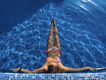 Young woman with colorful simmming suit relaxing in the turquoise water of the pool