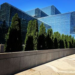 Trees by modern building against sky