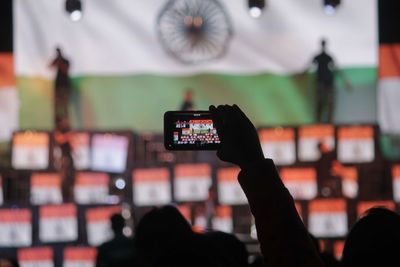 Cropped hand photographing indian flags on stage