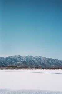 Scenic view of snowcapped mountains against clear blue sky