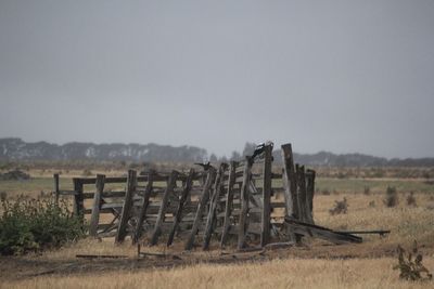 Wooden fence on field against clear sky