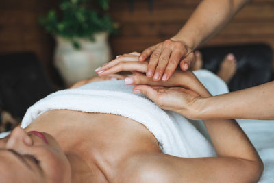 Attractive blonde young woman on couch with white linen enjoys hand massage inspa salon