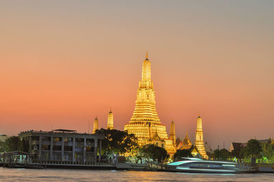 Temple by building against sky during sunset