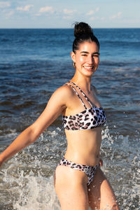 Portrait of woman in bikini standing at beach