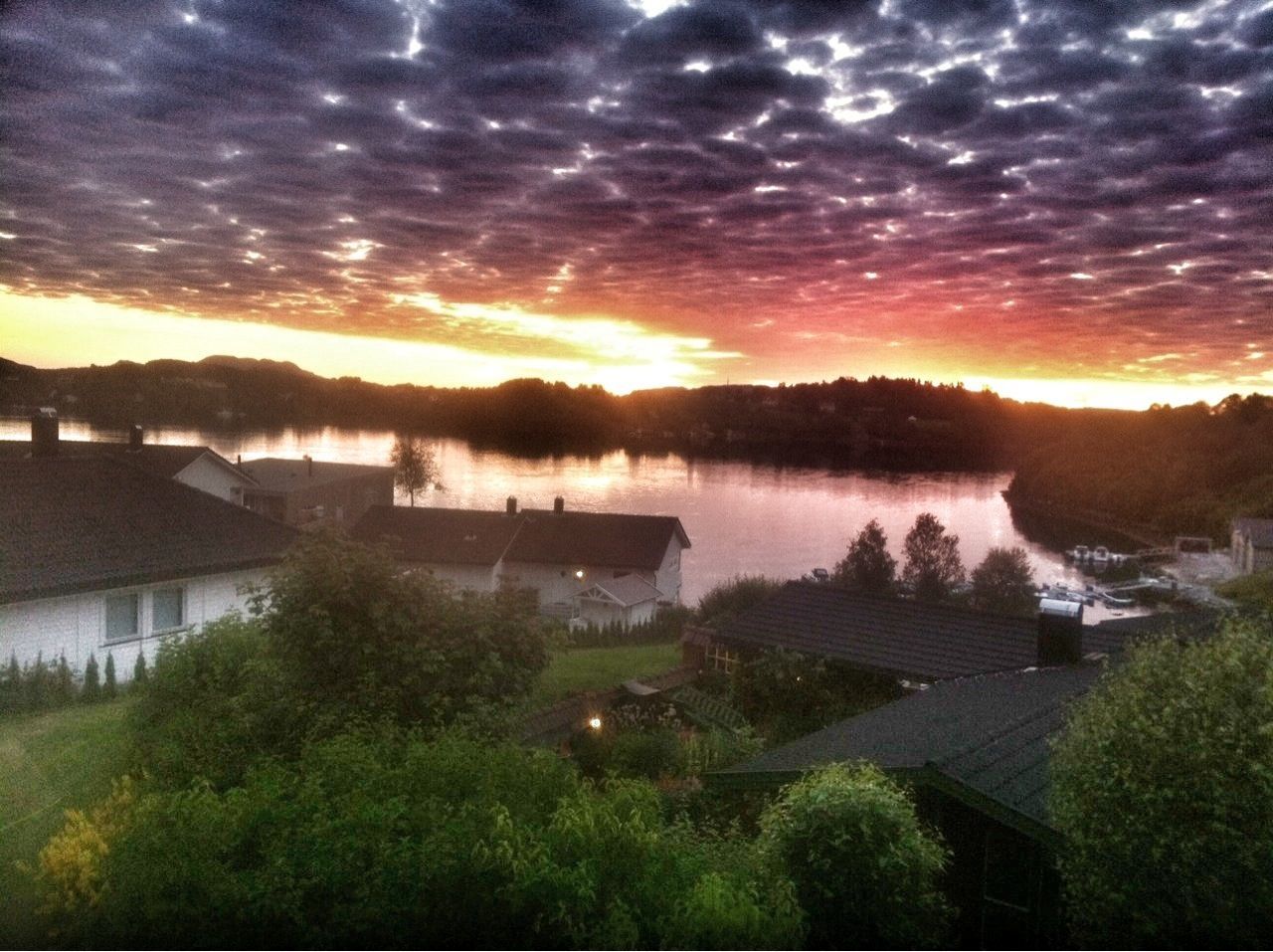 sunset, sky, cloud - sky, tranquil scene, scenics, lake, beauty in nature, tree, water, tranquility, cloudy, reflection, weather, nature, grass, landscape, cloud, sun, orange color, building exterior