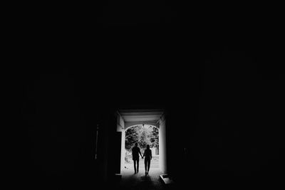 Rear view of man and woman walking in illuminated building