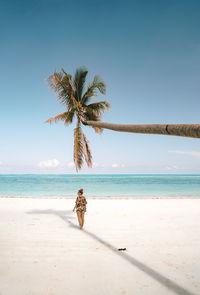 Woman walking under palm tree