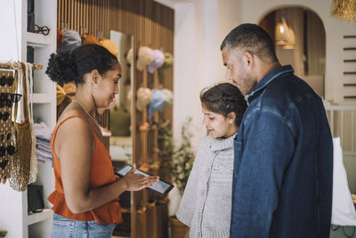 Saleswoman sharing digital tablet with customers at fashion boutique