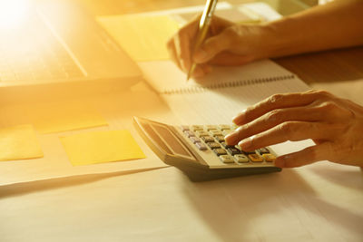 Cropped hands of person writing in book on table