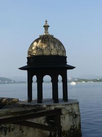 View of old building by sea against clear sky