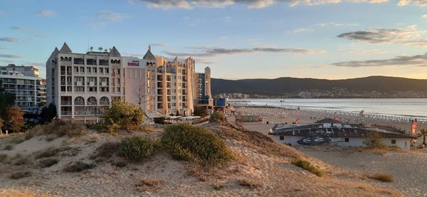 Buildings by sea against sky during sunset