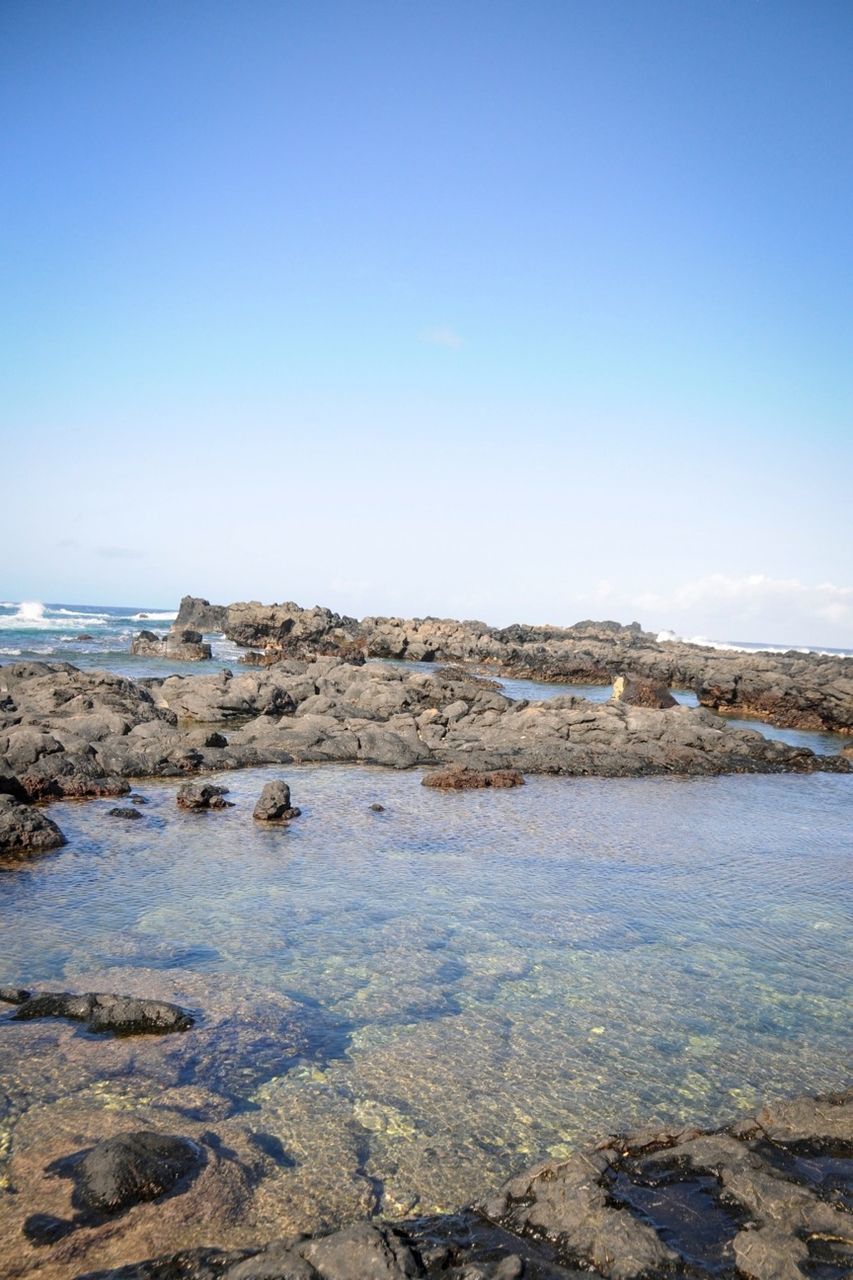 clear sky, water, copy space, blue, tranquil scene, tranquility, scenics, rock - object, beauty in nature, sea, nature, rock, shore, rock formation, beach, idyllic, stone - object, day, non-urban scene, outdoors