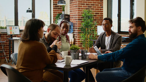 Portrait of smiling friends using mobile phone at restaurant