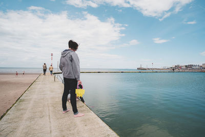 Rear view of man standing on sea against sky