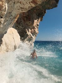 Rock formation in sea against sky