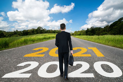 Rear view of man standing on road against sky