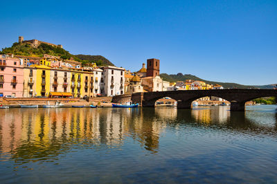 Arch bridge over river against clear blue sky in city
