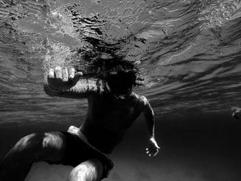 Shirtless man scuba diving undersea