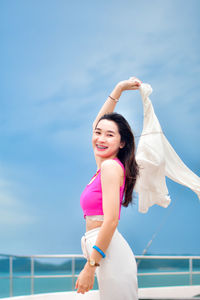 Portrait of young woman standing against sky